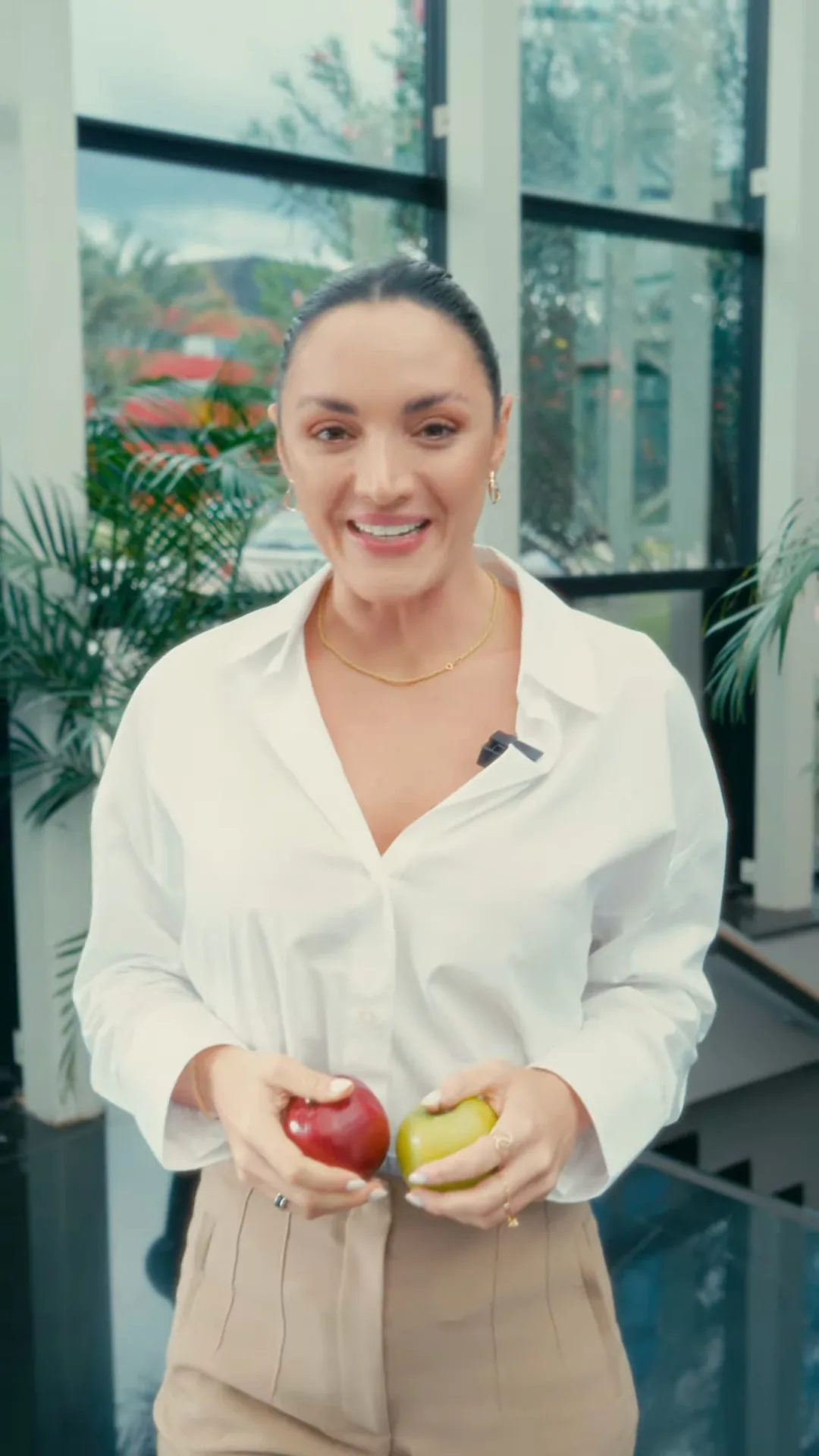 Quadro vertical de um vídeo da Sem Rótulo: apresentadora segurando duas frutas em um salão com paredes de vidro, usado como ilustração do formato de Stories